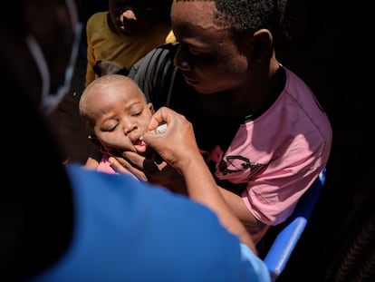 Un padre sostiene a su hijo mientras un trabajador le administra la vacuna contra la poliomielitis en el campo de refugiados de Dzaleka, en Malaui.