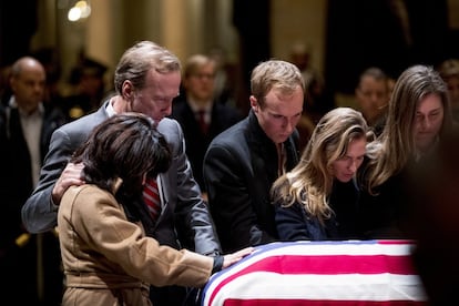 Neil Bush y su esposa Maria rinden honores al expresidente estadounidense George H.W. Bush, frente a su ataúd cubierto por la bandera americana.