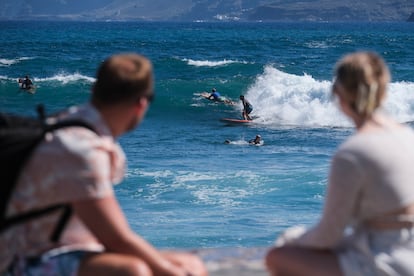 Dos turistas observan a los surfistas en el municipio tinerfeño de Puerto de la Cruz, el pasado 27 de septiembre.