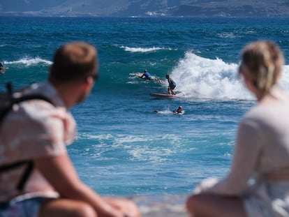 Dos turistas observan a los surfistas en el municipio tinerfeño de Puerto de la Cruz, el pasado 27 de septiembre.