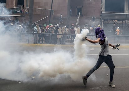 Un manifestante arroja un bote de gas lacrimógeno a la policía antidisturbios durante una protesta contra el presidente Nicolás Maduro, en Caracas.