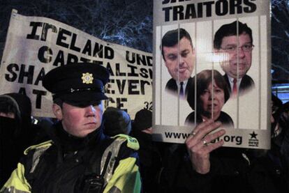 Un manifestante exhibe un cartel ante el Parlamento donde se llama traidores a los dirigentes irlandeses.