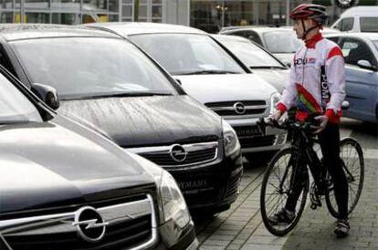Un ciclista observa vehículos de exposición del fabricante alemán Opel.