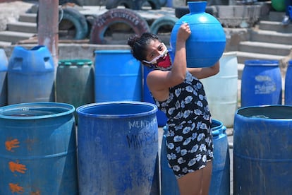 Una residente del barrio Los Almendros, en Ciudad Delgado (El Salvador) acarrea un recipiente con agua recibida de la Cruz Roja.