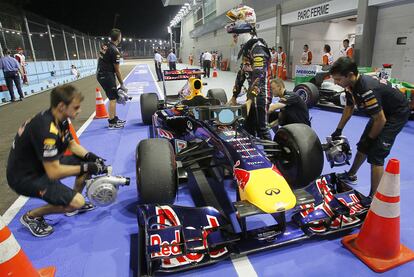 Sabastian Vettel observa su coche después de la sesión de entrenamientos libres mientras los mecánicos dan aire a los frenos.