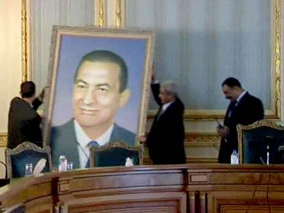 Funcionarios descuelgan un retrato de Mubarak de las paredes de un edificio gubernamental.