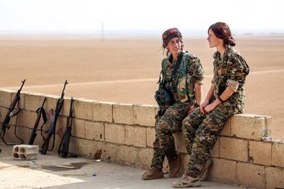 Dos mujeres, miembros de las Unidades de Protección Femenina (YPJ), dialogan junto a rifles de asalto Kalashnikov, en Mazraat Khaled, a unos 40 kilómetros de Raqa (Siria). 