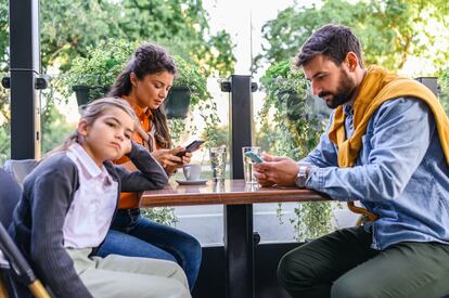 Una niña se aburre con sus padres en un bar.