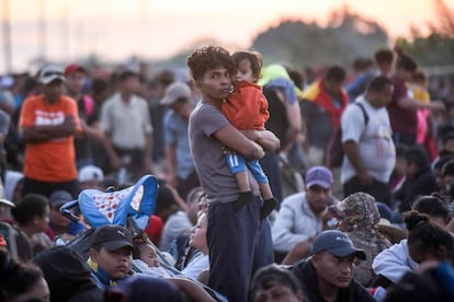 Un migrante centroamericano carga a su bebé en la última caravana de enero.