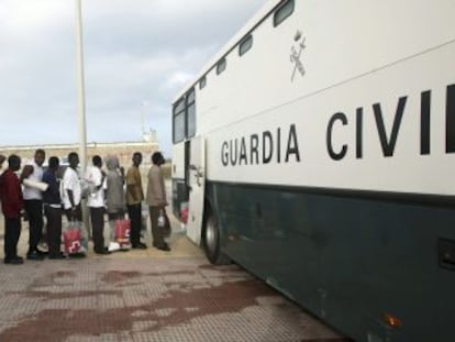 Un grupo de inmigrantes subsaharianos hace cola para subir a un autob&uacute;s de la Guardia Civil en Tarifa para ser trasladado a C&aacute;diz.