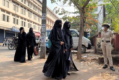 Alumnas con 'hiyab' llegan a clase mientras una mujer policía monta guardia en el exterior de una escuela pública femenina tras la reciente prohibición del hiyab, en la ciudad de Udupi, en el estado sureño de Karnataka, India, el pasado 16 de febrero.