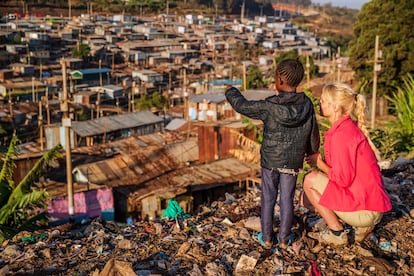Una niña africana, junto a una joven mujer caucásica, señala las casas del barrio de Kibera, en Kenia, África Oriental.