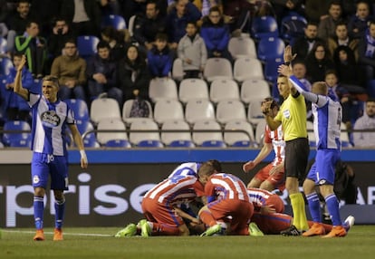 Jugadores del Deportivo y del Atlético asisten a Torres en el campo, tras el fuerte golpe que ha recibido en la cabeza por un choque con Alex Bergantiños.