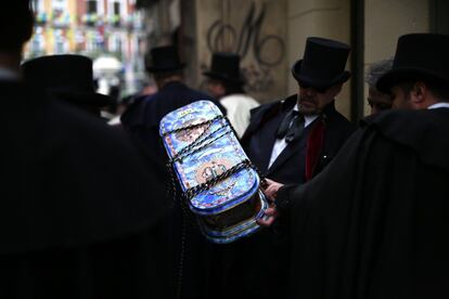 Un colorista ataúd contrasta con el atuendo fúnebre de los miembros de la cofradía.