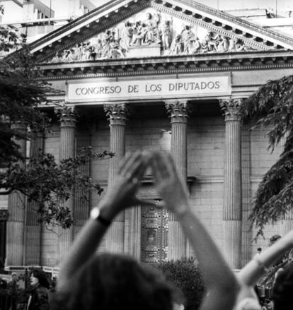 Una mujer hace el signo feminista en una manifestación a favor del aborto libre y gratuito a las puertas del Congreso de los Diputados, durante el debate sobre la despenalización parcial del aborto en casos de violación, grave peligro para la vida de la madre y malformaciones.