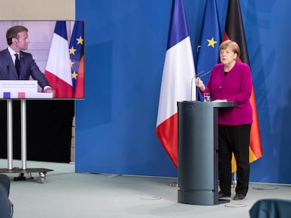 El presidente Emmanuel Macron, en pantalla, y la canciller Angela Merkel, durante una rueda de prensa, este lunes, en Berlín.