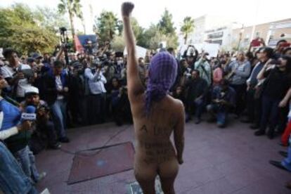 A naked woman raises her fist during a march for the missing 43 trainee teachers. The writing on her body reads, "No more feminicides, stop violence".