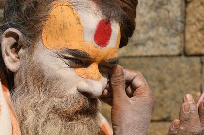 Un Sadhu hindú se pinta la cara junto al templo Pashupatinath en Katmandú.
