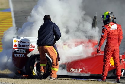 Un operario del circuito de Valencia se emplea con un extintor para tratar de apagar el incendio en el Ferrari.