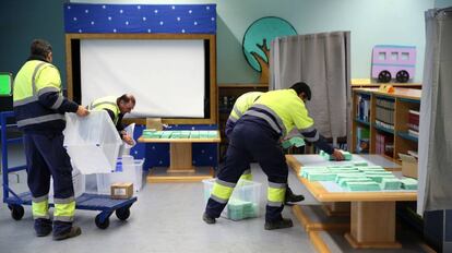 Operarios preparan las urnas y papeletas electorales en una biblioteca municipal, este sábado Alcalá de Guadaira.