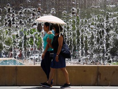 CÓRDOBA, 12/06/2022.- Varias mujeres se protegen del sol con un paraguas para a su paso junto a una de las fuentes de la Córdoba. EFE/Salas
