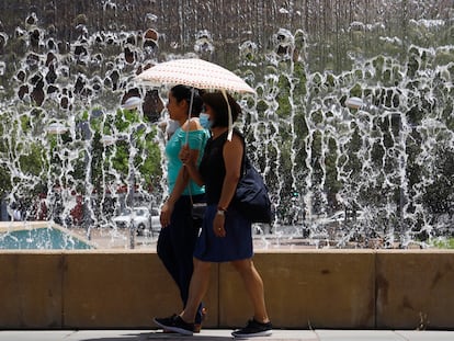 CÓRDOBA, 12/06/2022.- Varias mujeres se protegen del sol con un paraguas para a su paso junto a una de las fuentes de la Córdoba. EFE/Salas
