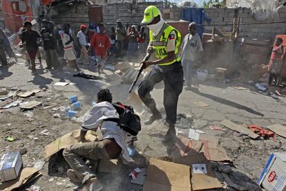 Um policial aponta a um jovem no chão durante uma jornada de distúrbios e saques na zona comercial de Porto Príncipe (18/01/2010).