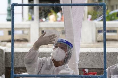 Una sanitaria desinfecta láminas de plástico después de recoger muestras para las pruebas de coronavirus en Bangkok, Tailandia.