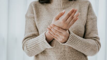 Cropped shot of woman in sweater holding her wrist pain