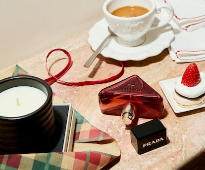 Vela perfumada con esencia de palo santo de LOEWE Perfumes, un presente de lujo en su vasija de terracota esmaltada y con una duración de unas 30 horas, y frasco de perfume rellenable Prada Paradoxe Radical Essence de PRADA.Servilleta y taza, ambos de MAISONS DU MONDE.