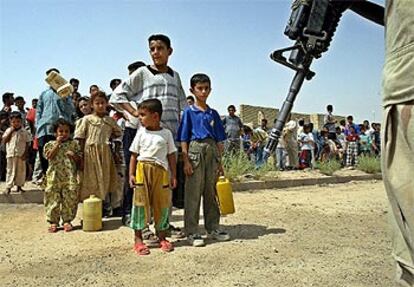 Soldados estadounidenses registran a varios niños iraquíes en una cola para el reparto de gasolina en Faluga.