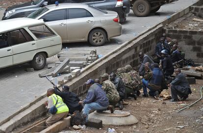 Miembros de la polic&iacute;a, ej&eacute;rcito y personal de seguridad buscan refugio tras una pared en el exterior del centro comercial. 