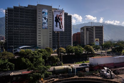 Dos anuncios comparten la fachada de un edificio: uno recién colocado promocionando una clínica de cirugía estética, junto a otro descolorido con las imágenes de personajes como Simón Bolivar, Hugo Chávez y Nicolás Maduro, en la carretera Prados del Este, en Caracas, el 12 de agosto de 2022.