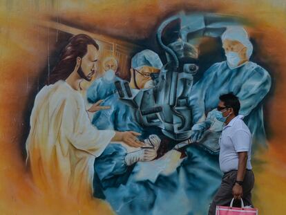 Un hombre camina junto a un mural relacionado con la pandemia de covid-19 en el centro de Mérida, Yucatán.