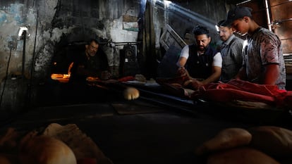 Palestinos hornean pan en horno de leña, en medio de la escasez de combustible y energía, este lunes en Jan Yunis.