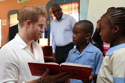 El príncipe lee a unos niños un libro de historia en al Holy Trinity Primary.