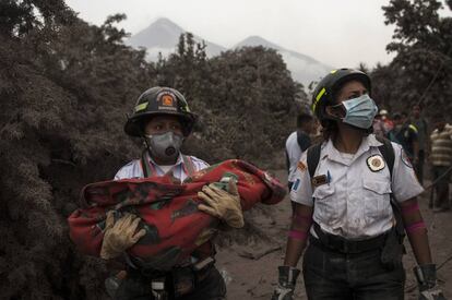 Dos miembros de los equipos de emergencia, con un bebé en brazos.