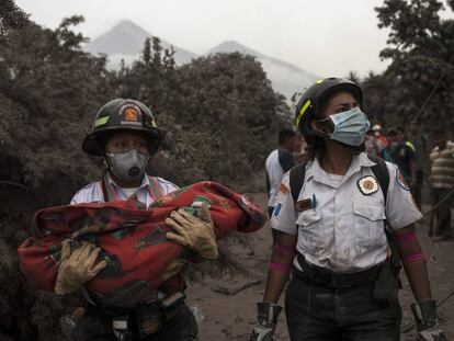 Dos miembros de los equipos de emergencia, con un bebé en brazos.