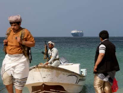 Hombres armados permanecen en la playa mientras el buque comercial Galaxy Leader, incautado por los Hutíes.