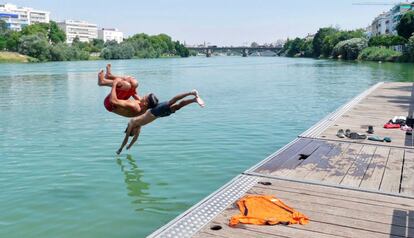 Dos jóvenes se lanzan al río Guadalquivi hoy en Sevilla, una de las ciudades más afectadas por la fuerte ola de calor que está provocando temperaturas récord estos dias. 