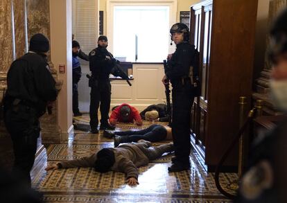 La policía del Capitolio detiene a los manifestantes en uno de los pasillos de la Cámara donde se desarrollaba la sesión para ratificar la victoria del Colegio Electoral del presidente electo Joe Biden.