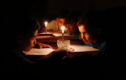 Niños palestinos leen a la luz de las velas debido a cortes del suministro eléctrico en Gaza.