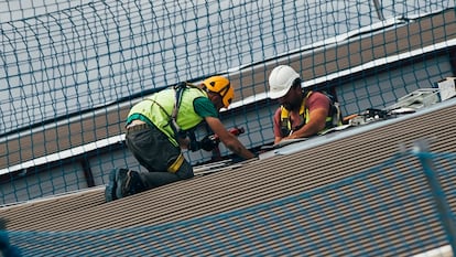 Unos trabajadores trabajan en la cubierta de una nave industrial de Pocomaco en A Coruña.