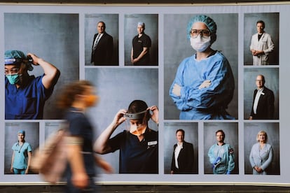 Una mujer con mascarilla pasa junto a una exposición de fotografías al aire libre sobre trabajadores sanitarios en Melbourne (Australia).