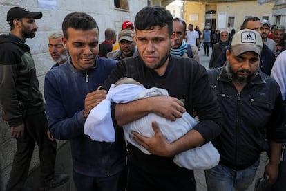 Un hombre lleva el cadáver de un bebé palestino muerto este martes en un ataque israelí en Ciudad de Gaza.