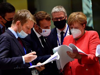 Pedro Sánchez, Emmanuel Macron, y Angela Merkel examinan documentos durante la cumbre de la UE en Bruselas en la que se aprobó el fondo de recuperación.