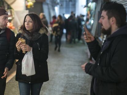 Dos clients de La Boqueria menjant en els passadissos del mercat.