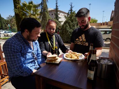 Una camarera sirve unas tapas a dos clientes en un bar del barrio del Zaidín de Granada.