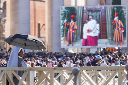 Fieles observan en una pantalla gigante instalada frente a la basílica de San Pedro el inicio del cónclave.