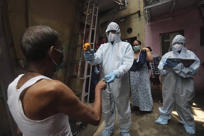 Un médico toma la temperatura a un hombre durante un control rutinario en Dharavi (India).